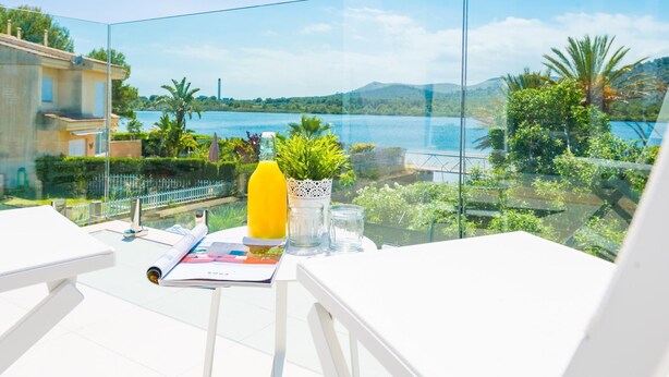 Een balkon met een helder uitzicht op een meer, begroeiing en verre bergen.