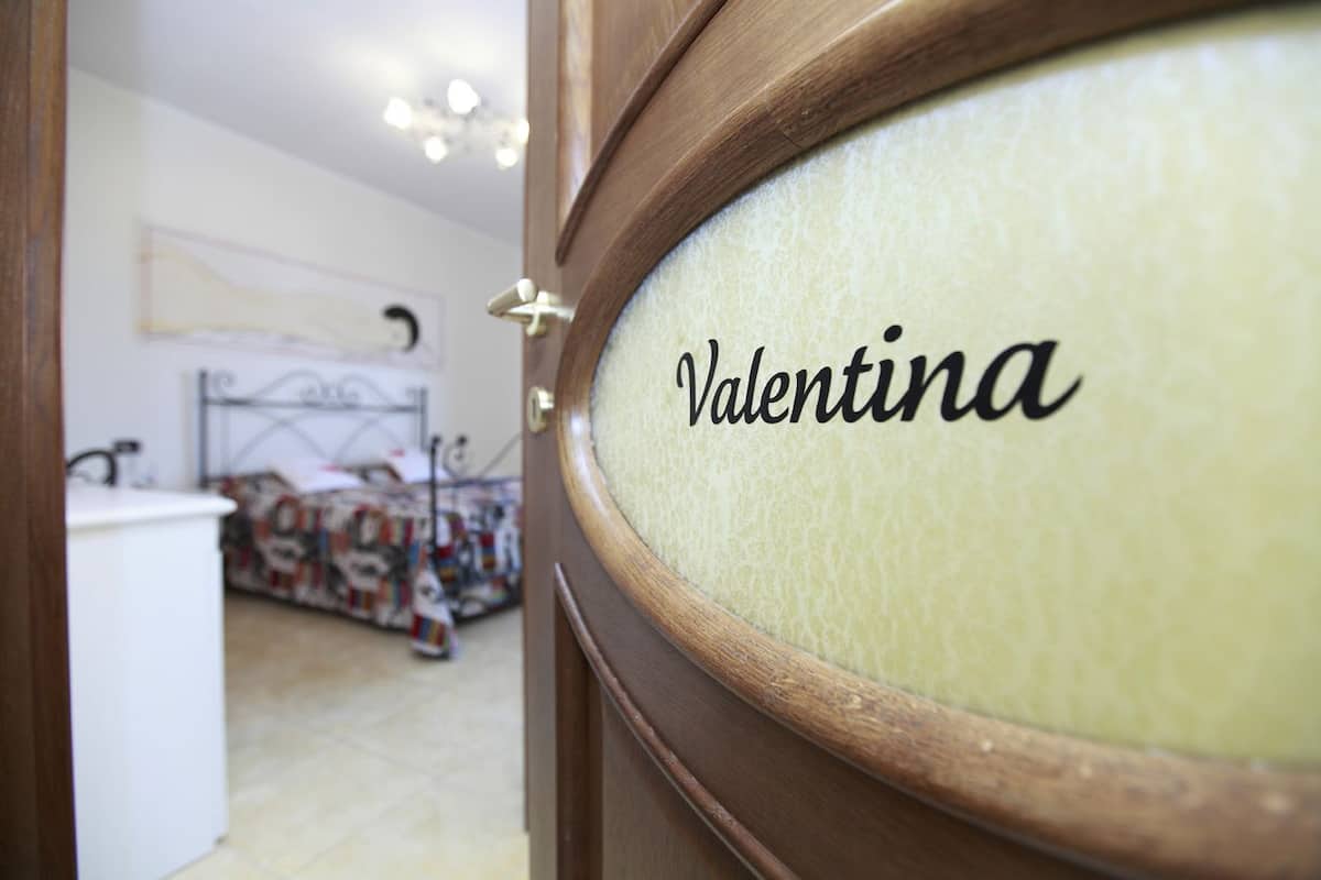 A room with a bed, a dresser, and a mirror with the name 'Valentina' on it.