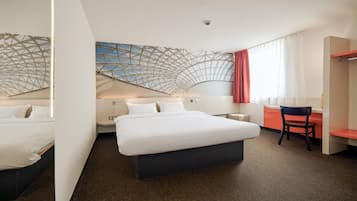 Habitación de hotel con una cama grande, un escritorio y una silla. Hay una ventana con cortinas y vistas al cielo.