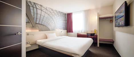 Een moderne hotelkamer met een groot bed, een bureau, een stoel en een televisie.