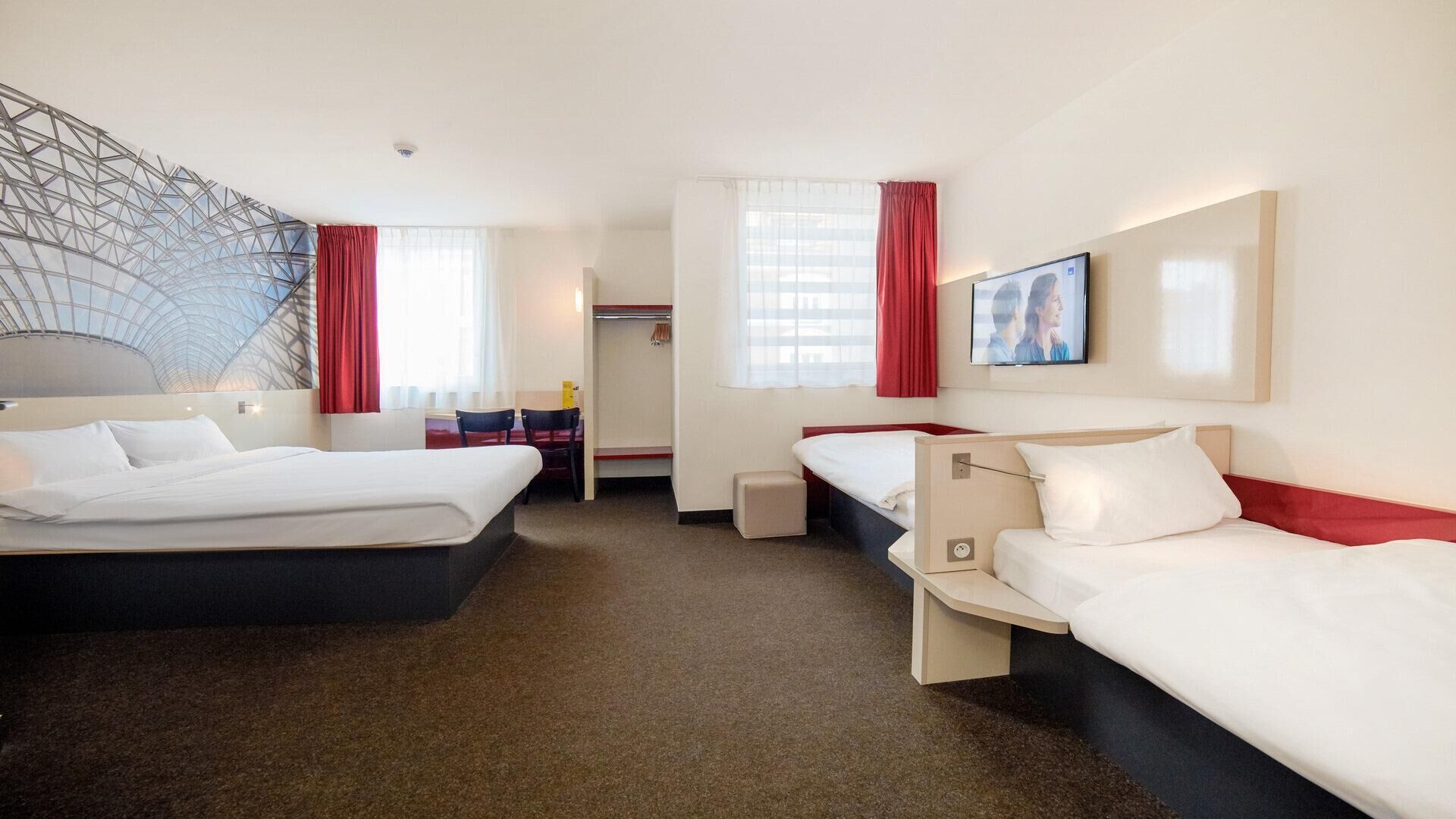 A hotel room with two beds, a desk, and a walk-in closet.