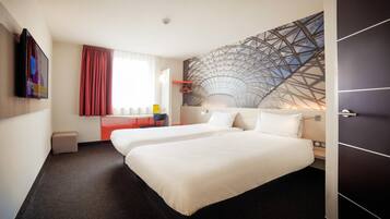 A hotel room with two beds, a large window with curtains, a wall-mounted TV, and a unique geometric wall design.