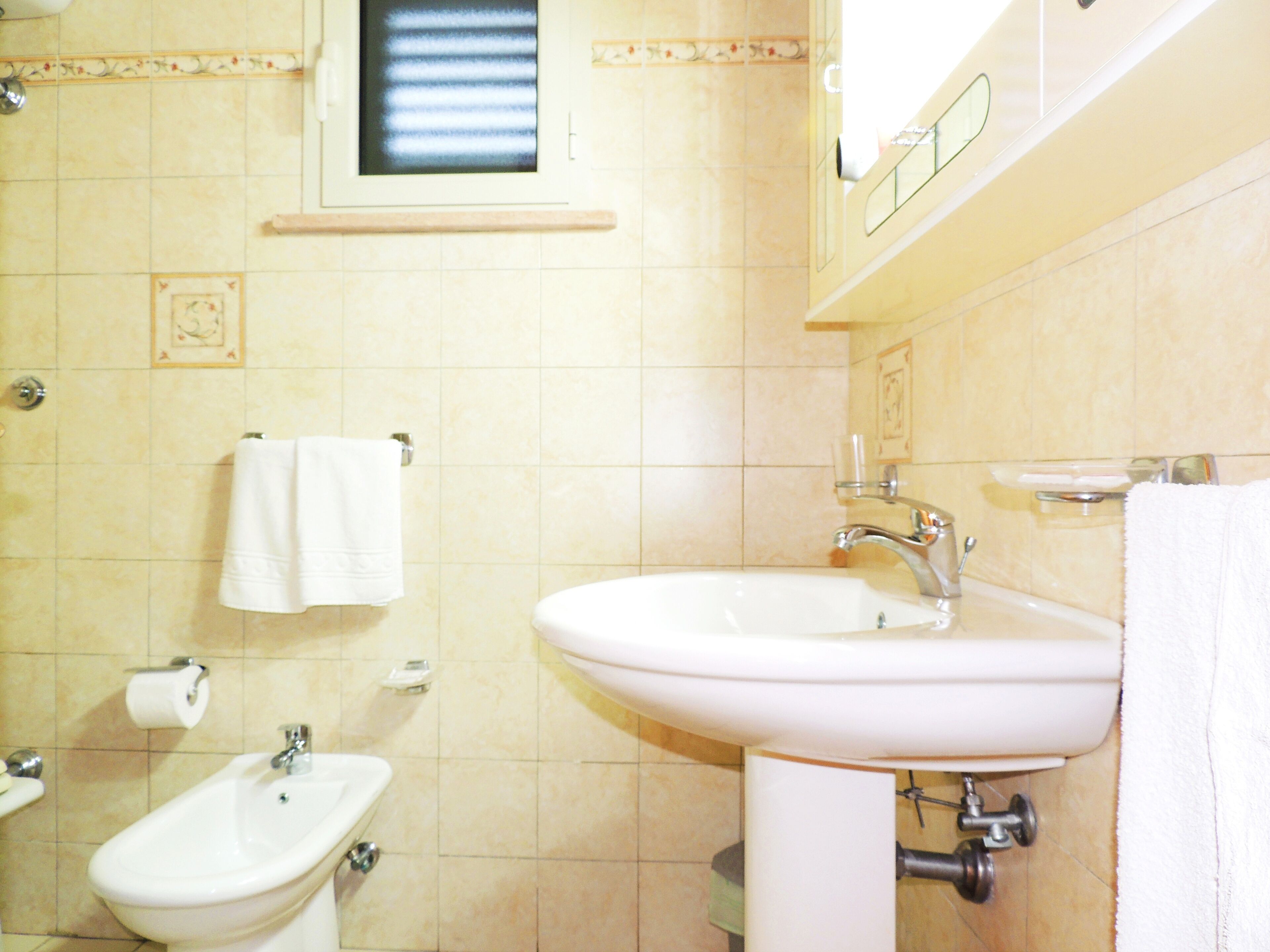 A bathroom with a sink, bidet, and toilet.
