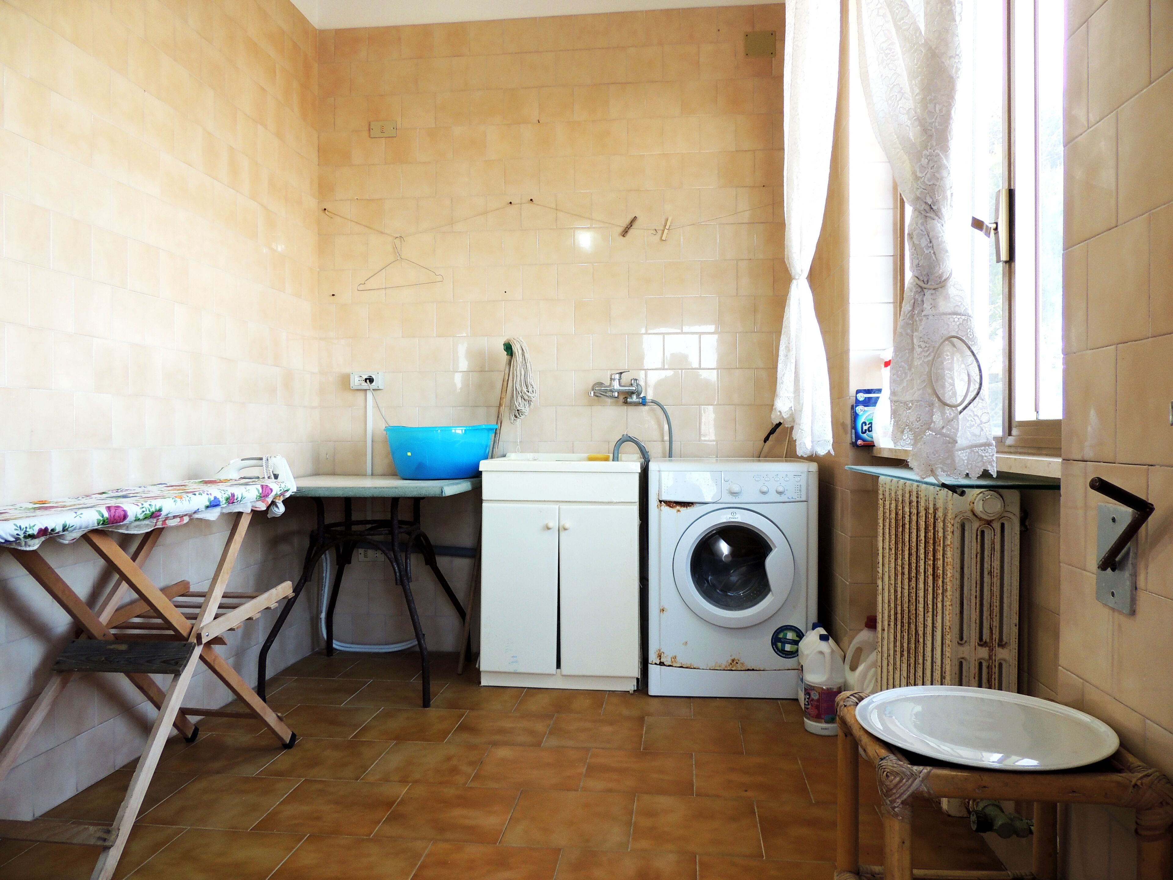A compact kitchen with a washing machine, a sink, and a table with a blue basin.