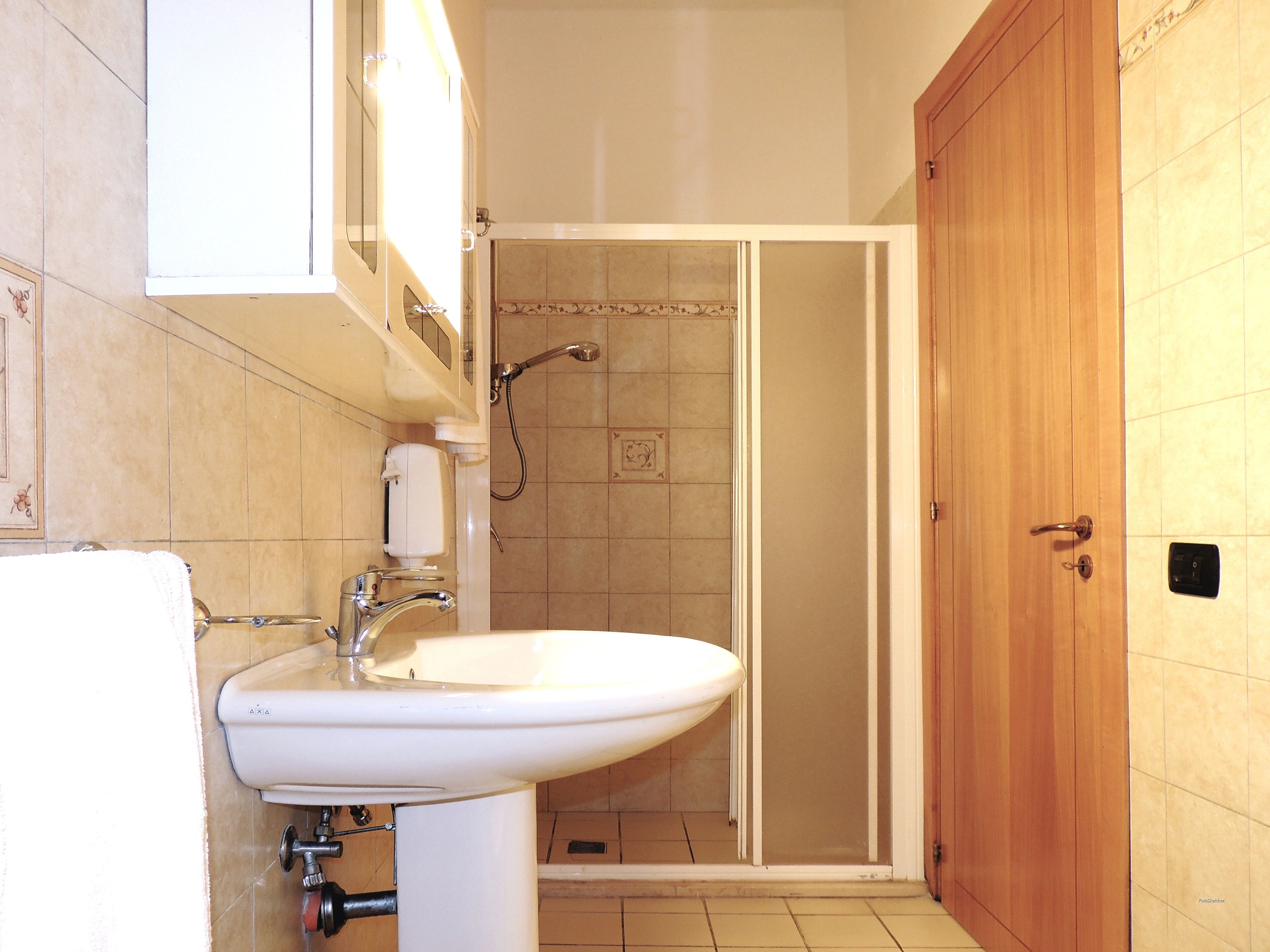 A bathroom with a sink, mirror, and shower area.