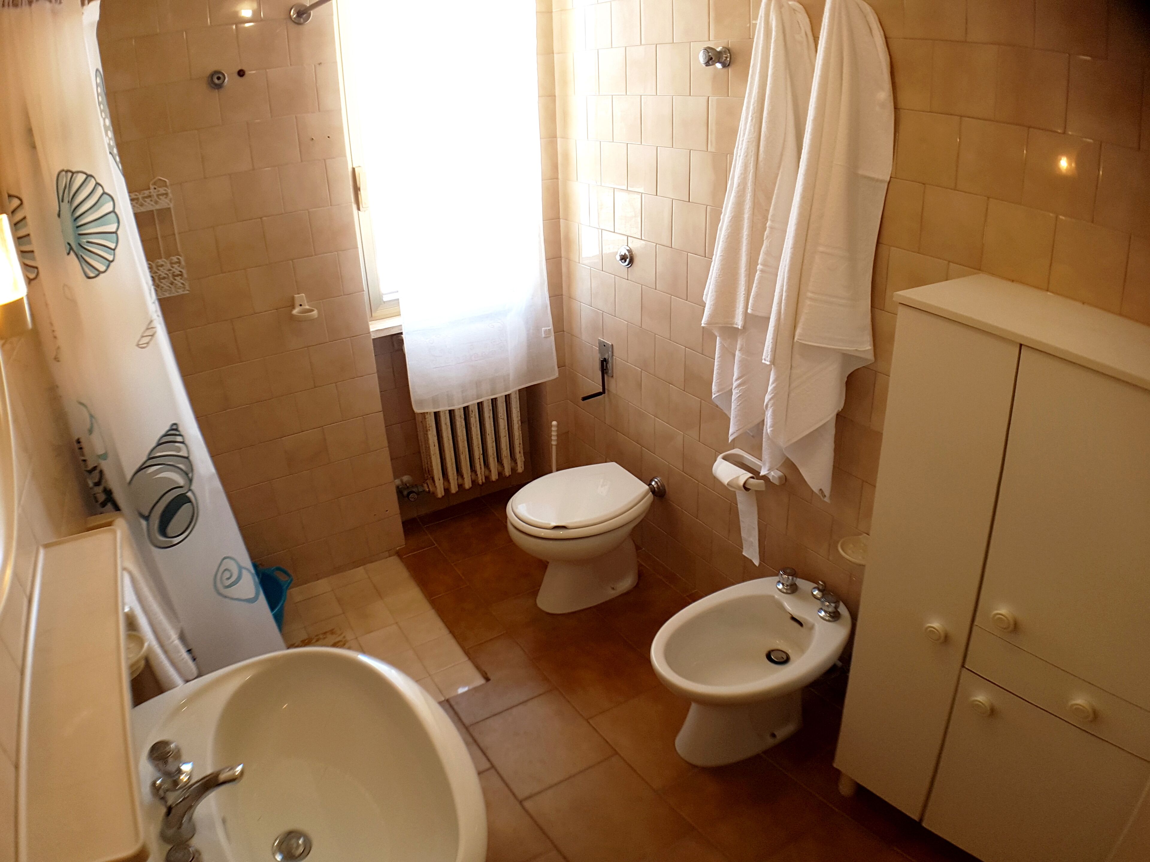A bathroom with a toilet, bidet, sink, and a shower area.
