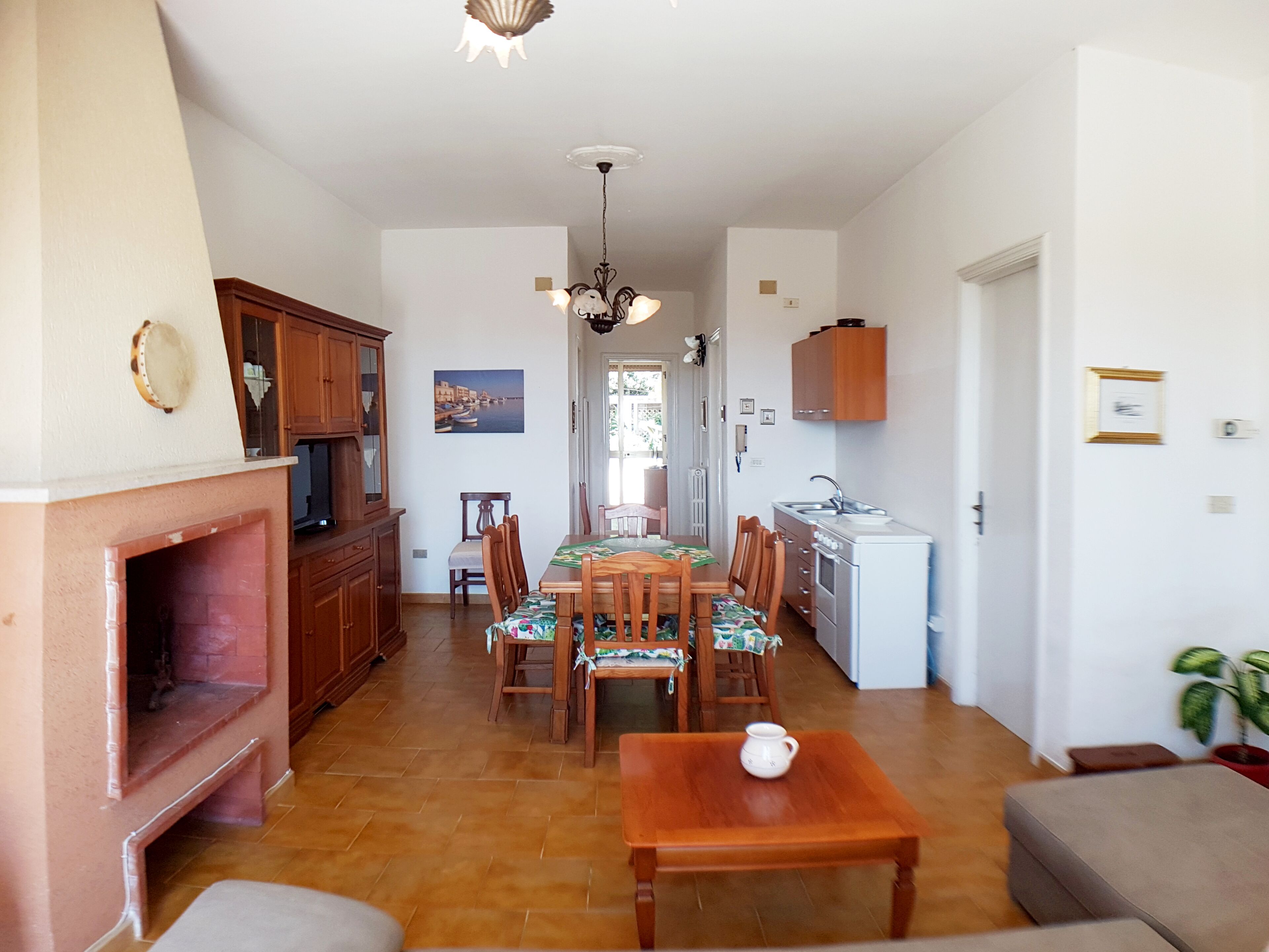 Een ruime woonkamer met een open haard, eethoek en keuken.