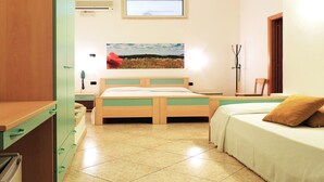 A bedroom with a bed, a bedside table, a chair, a TV, and a window. - Hotel Porto Badisco (Otranto)