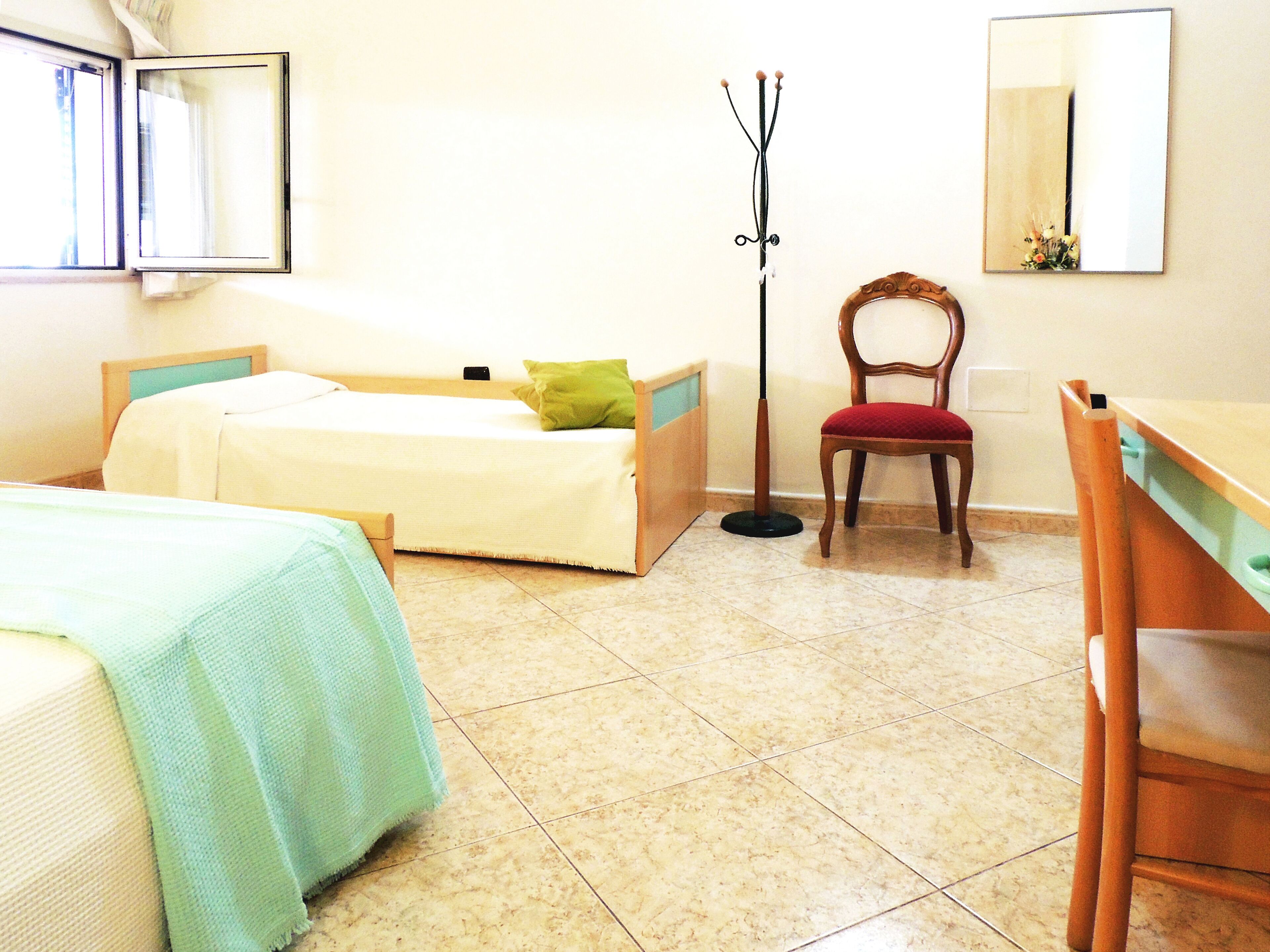 Una habitación con una cama, una silla, un escritorio y un espejo.