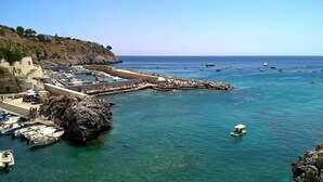 A coastal town with a marina, rocky cliffs, and clear blue sea. - Hotel Porto Badisco (Otranto)
