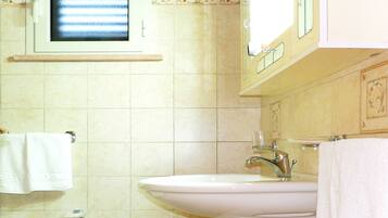 Un baño con lavamanos, espejo y ventana.