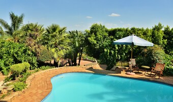 Una piscina al aire libre, sombrillas, sillones reclinables de piscina