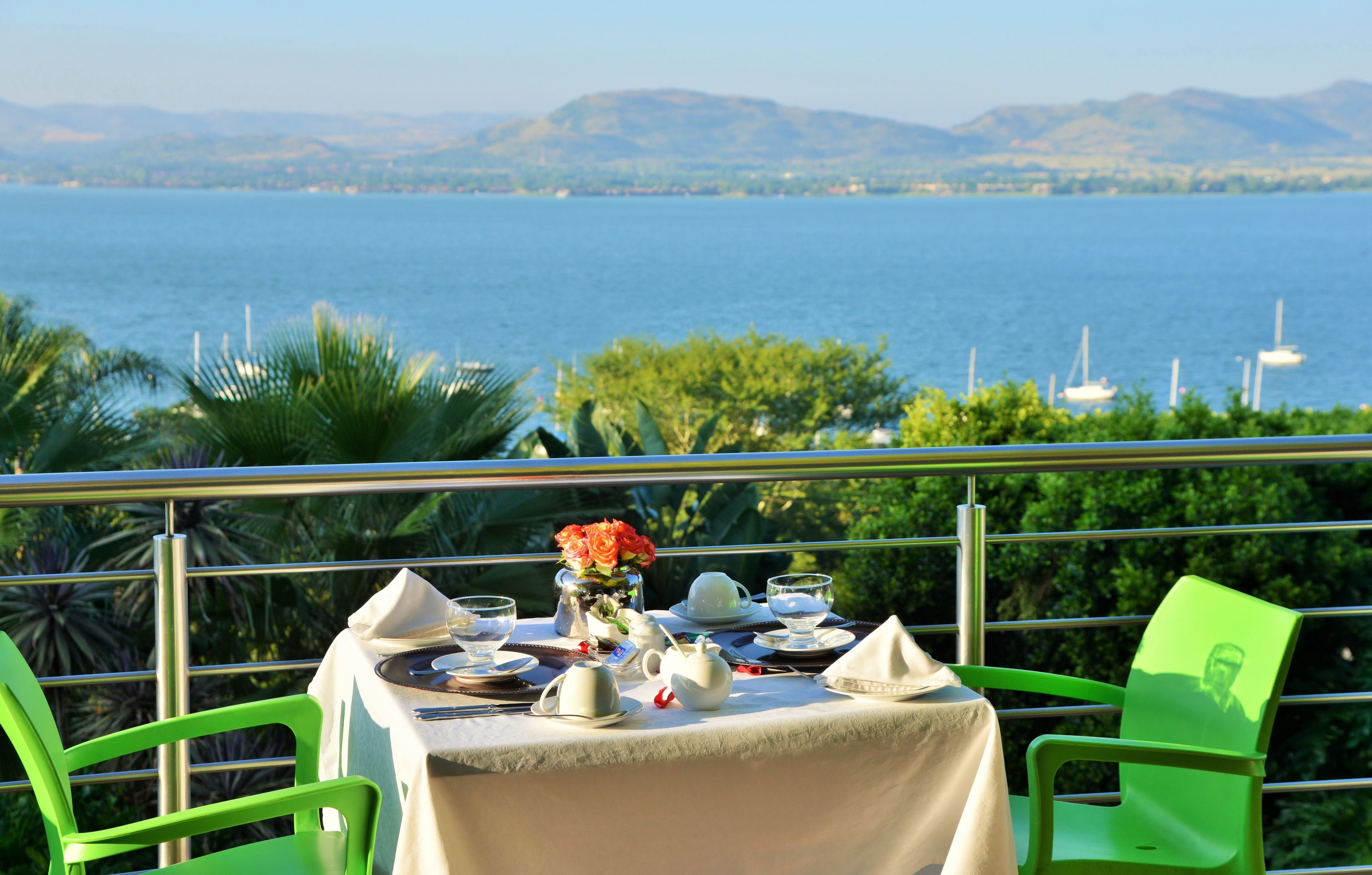 A table set for two with a view of the sea and mountains in the background.