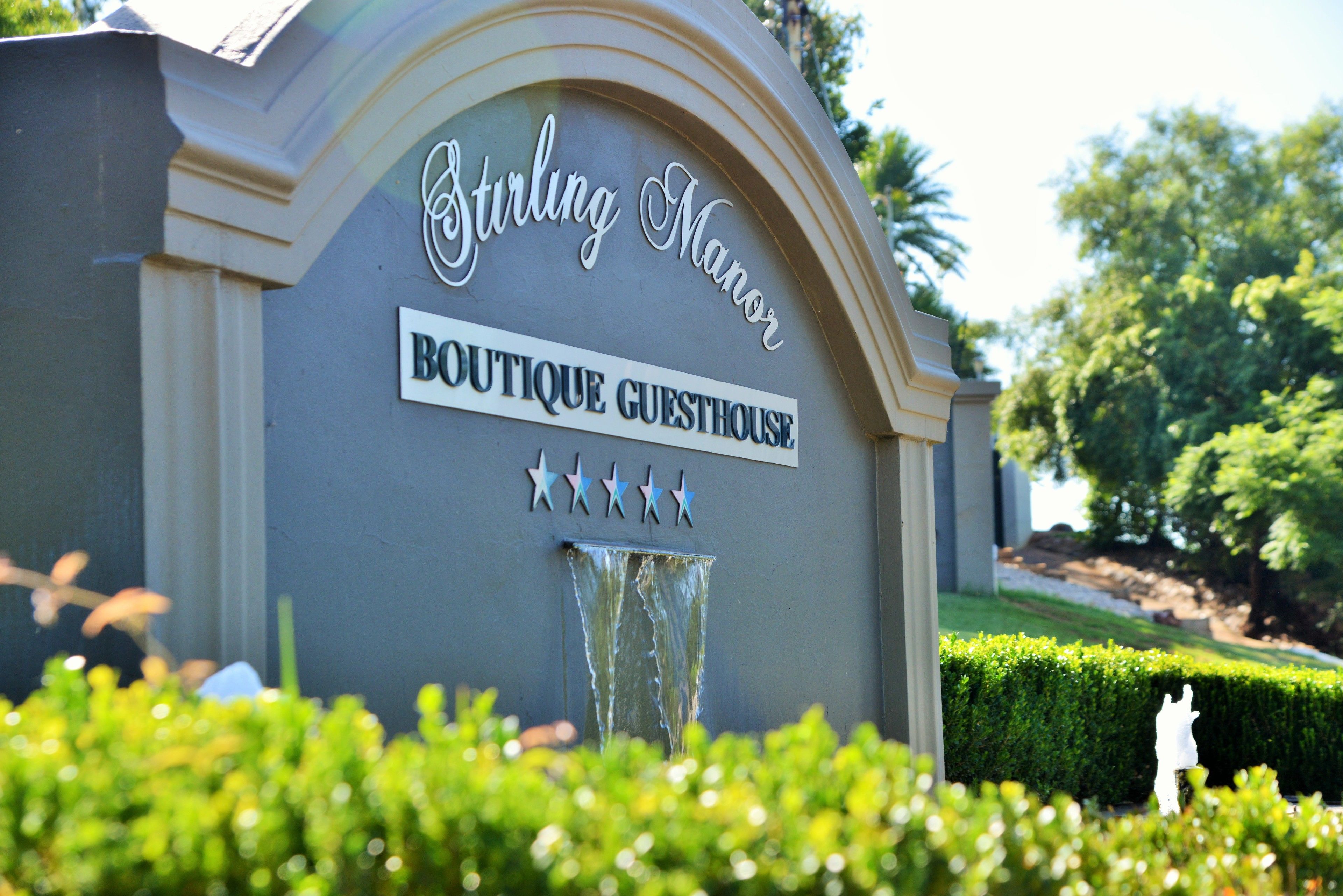 A sign for 'Stirling Manor Boutique Guesthouse' with a water feature and star decorations.