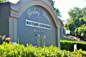 Letrero de 'Stirling Manor Boutique Guesthouse' con una fuente de agua y decoraciones de estrellas.