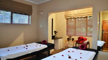 Relax in a serene space with two treatment tables, towels, and a vase of flowers.