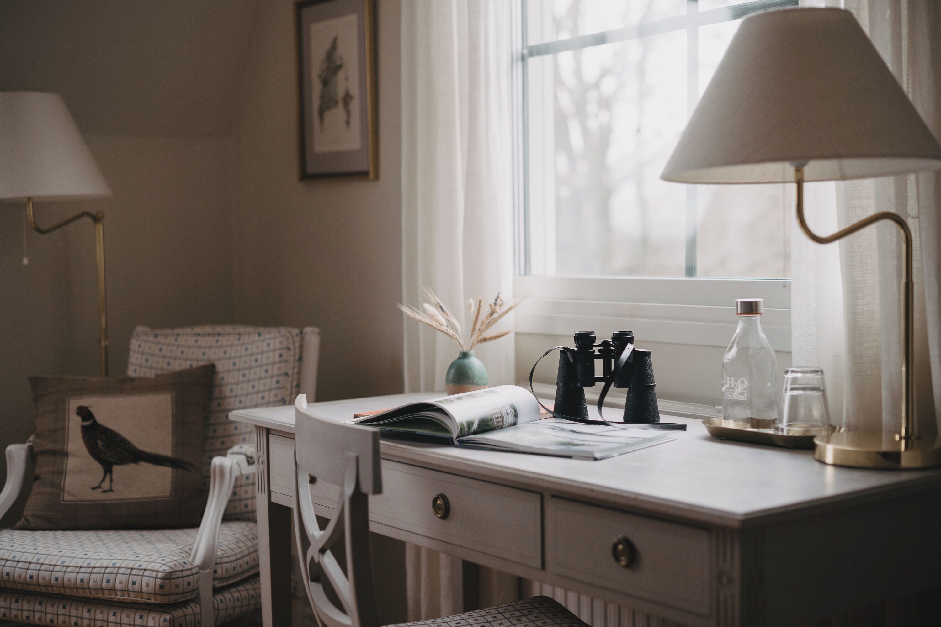 Un espacio de trabajo ordenado con escritorio, silla, lámparas y una ventana con luz natural.