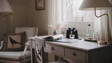 Un espacio de trabajo ordenado con escritorio, silla, lámparas y una ventana con luz natural.
