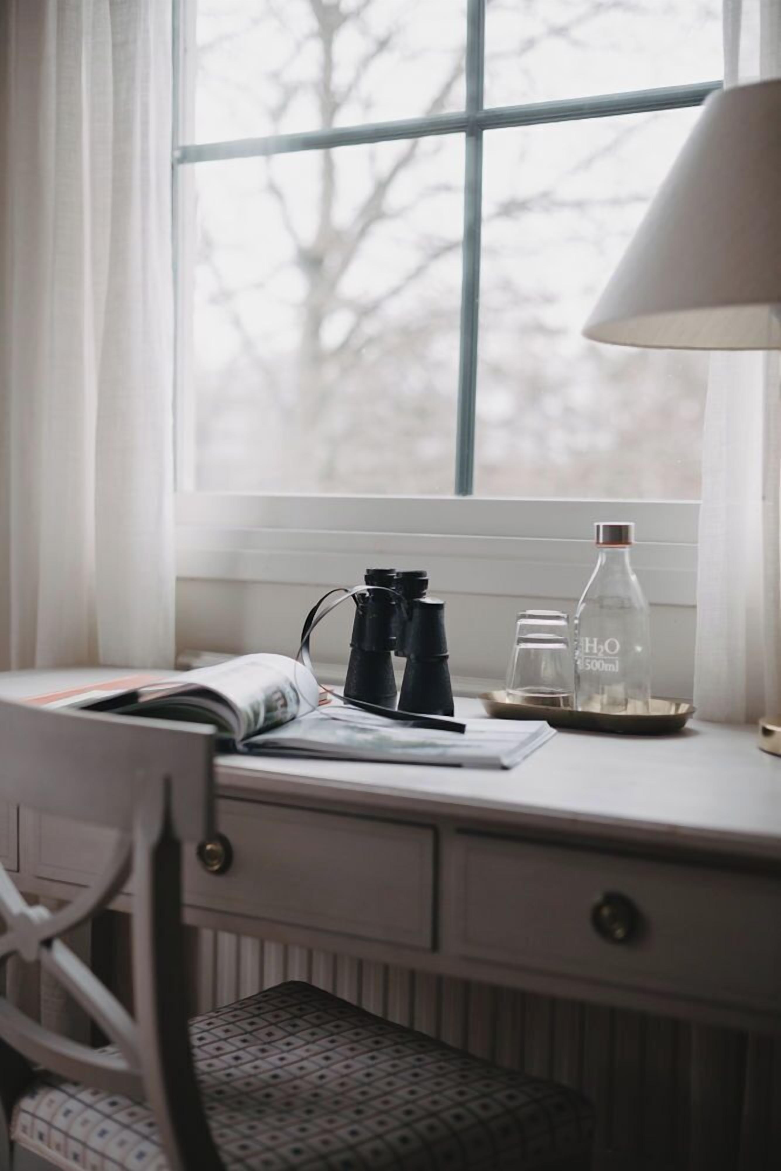 A desk with a lamp, binoculars, a water bottle, and a glass.