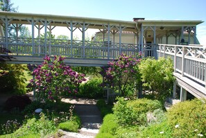 A wooden bridge with a railing, surrounded by lush greenery and flowering plants. - Engsholms Slott - Adults Only (Morko)