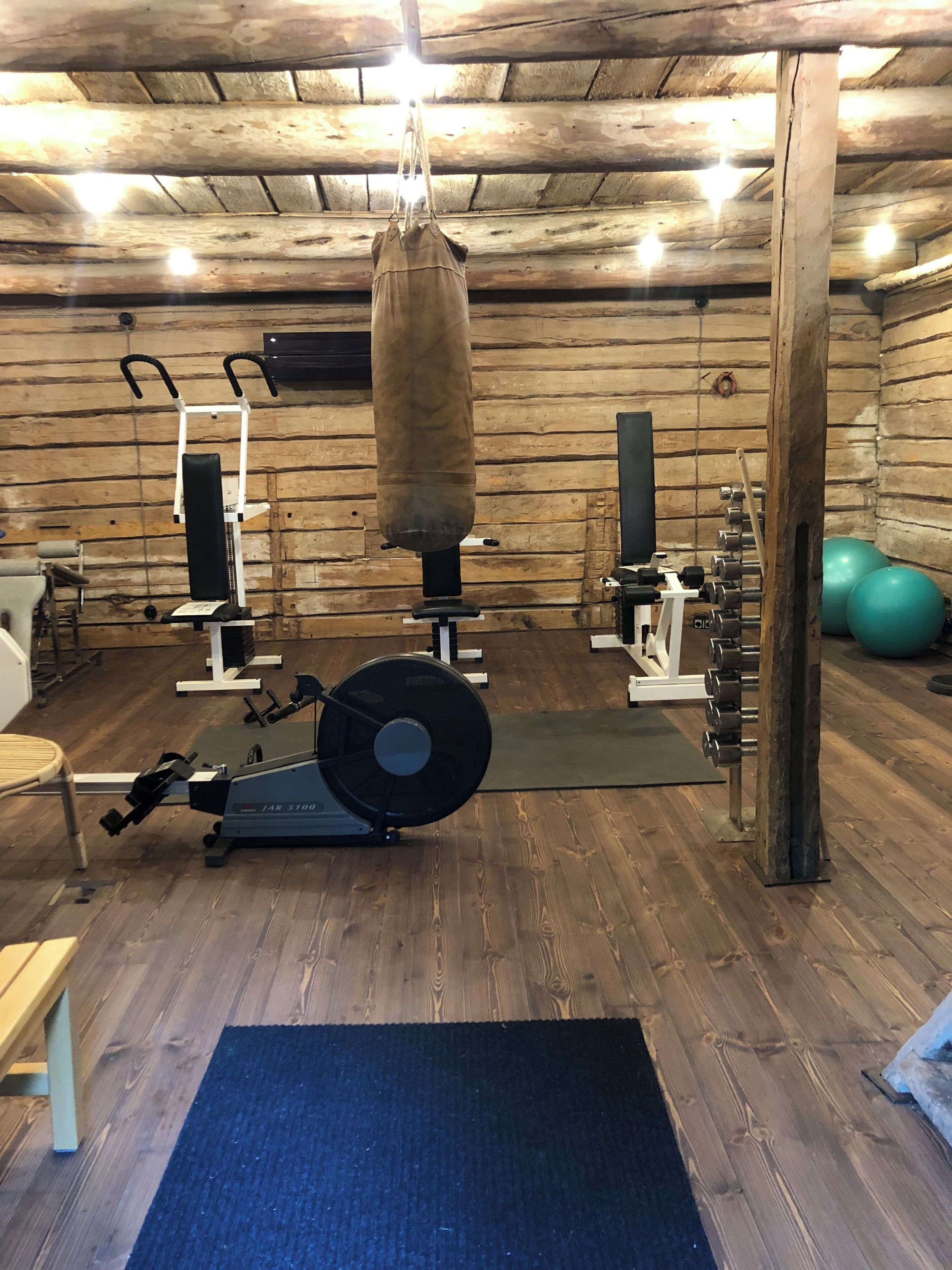 Un gimnasio con un saco de boxeo, máquinas de pesas y pelotas de ejercicio.