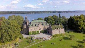 A large, historic building with a central dome and multiple wings, surrounded by lush greenery and a lake. - Engsholms Slott - Adults Only (Morko)
