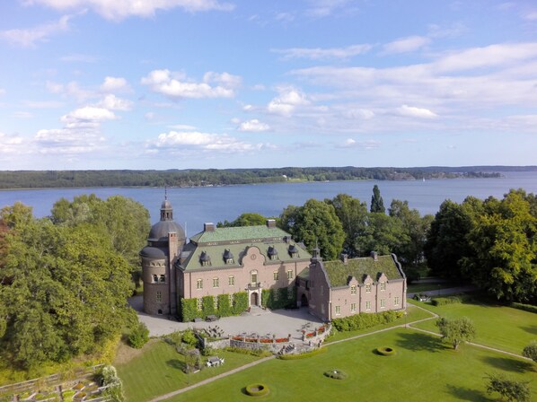 A large, historic building with a central dome and multiple wings, surrounded by lush greenery and a lake. - Engsholms Slott - Adults Only (Morko)