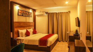 A hotel room with a bed, a desk, a chair, an air conditioning unit, and a television. - Rest Inn By Sublime (Bengaluru)