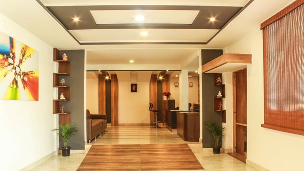 A hotel lobby with a wooden reception desk, a reception area, and a seating area with a sofa. - Rest Inn By Sublime (Bengaluru)
