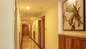 A hotel hallway with wooden doors, a wooden panel wall, and a framed abstract painting. - Rest Inn By Sublime (Bengaluru)