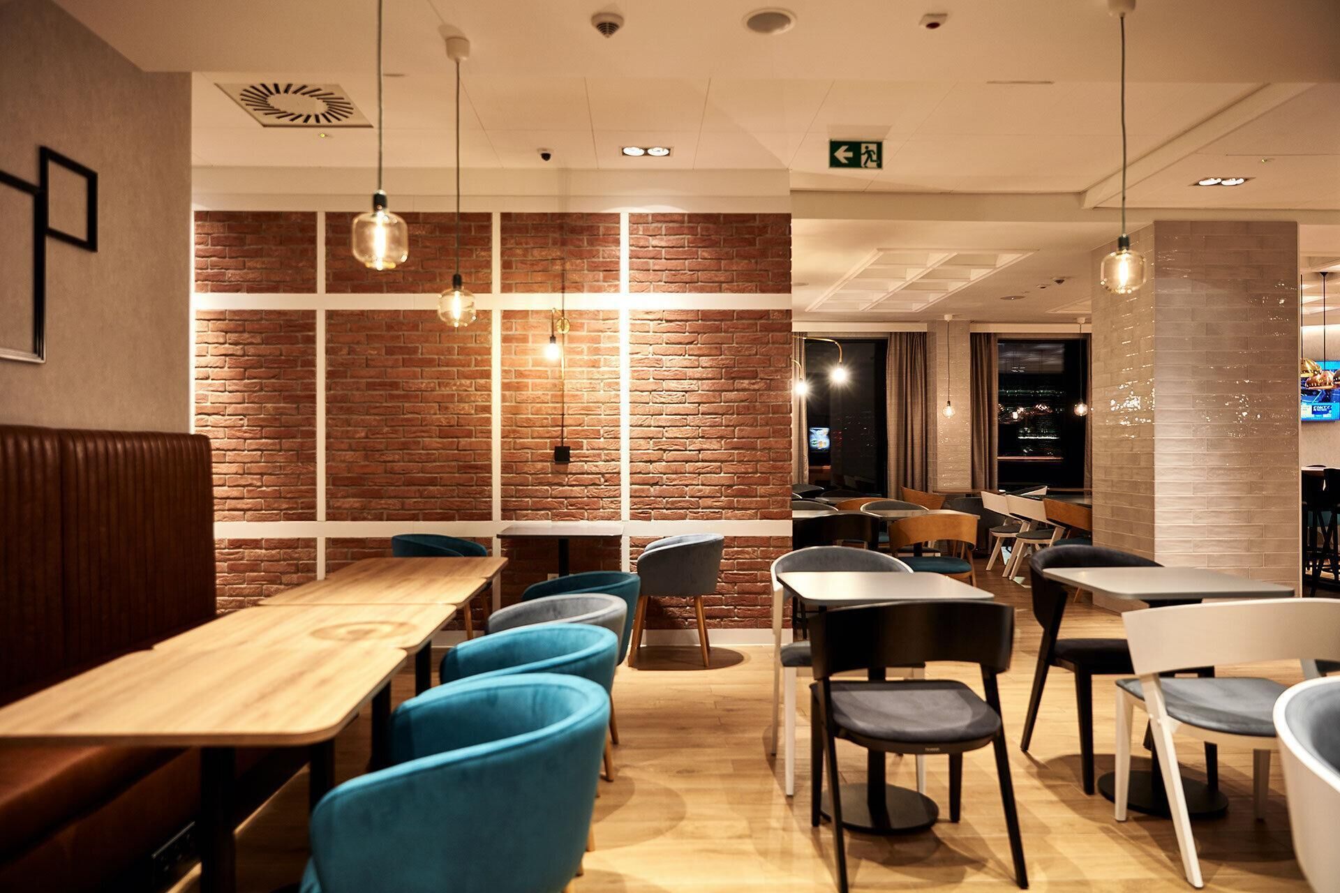 A restaurant interior with brick walls, wooden tables, and blue chairs.