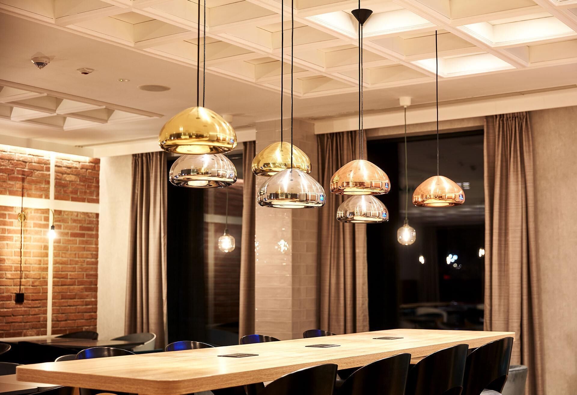 A conference room with a long table, multiple chairs, and pendant lighting.