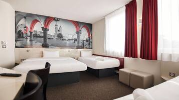 Habitación de hotel con dos camas, un escritorio y un cuadro grande con una vista panorámica de la ciudad.