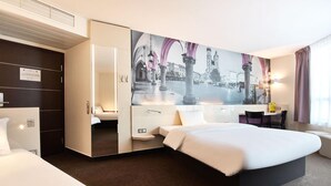Een moderne hotelkamer met een groot bed, een zithoek en een stadsgezicht muurschildering.