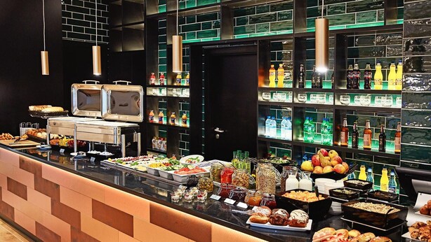 Een buffetgedeelte met diverse gerechten, drankjes en een koelkast voor zelfbediening.