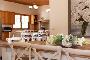 A kitchen with wooden cabinets, a dining area with white chairs, and a table with a floral centerpiece.