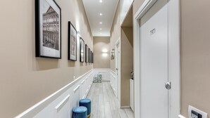 A hallway with framed pictures on the walls, a white door with a sign, and a light switch on the wall. - RAGGIO DI SOLE - ATAROOMS Collection (Naples)