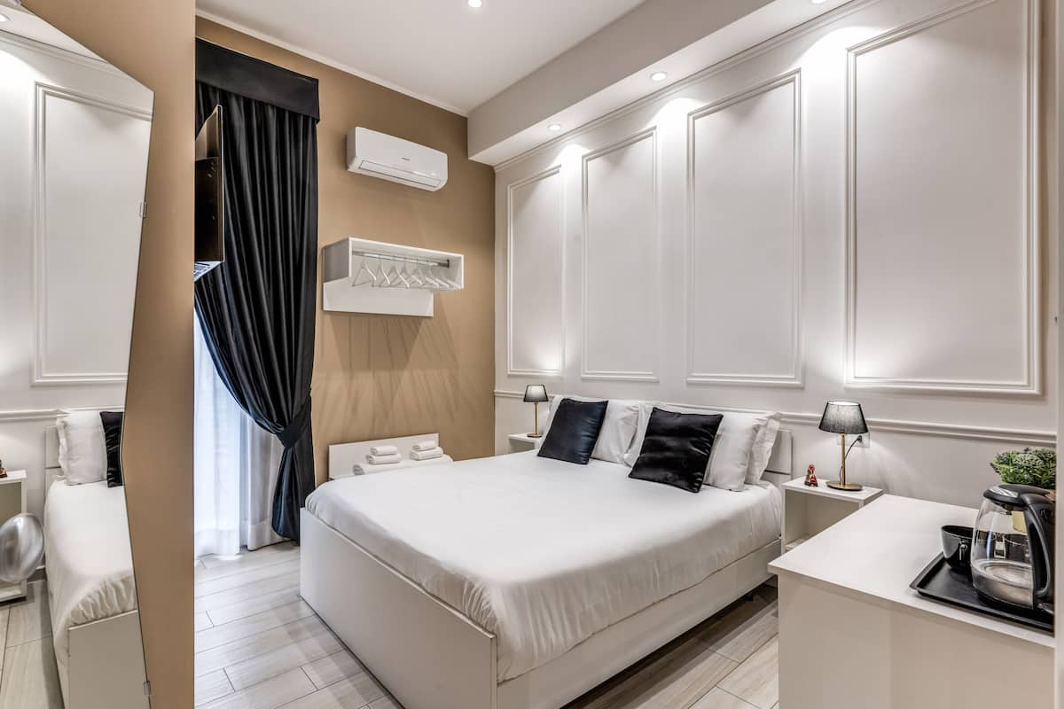 A modern hotel room with a large bed, bedside tables, a desk, and a coffee machine.