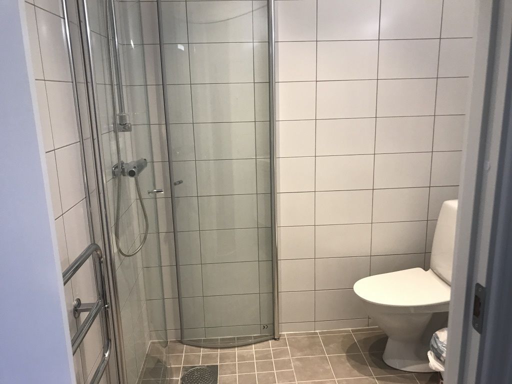 A bathroom with a glass-enclosed shower, a toilet, and tiled walls.