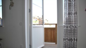A room with a wooden deck, a white door, and a patterned curtain. - Sjöhuset (Ellos)
