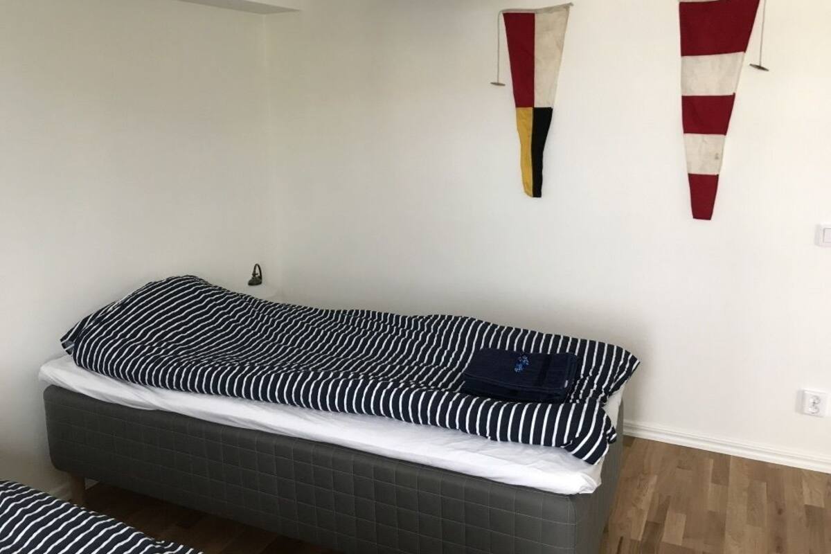 A bedroom with a single bed, a hanging light fixture, and two wall-mounted flags.