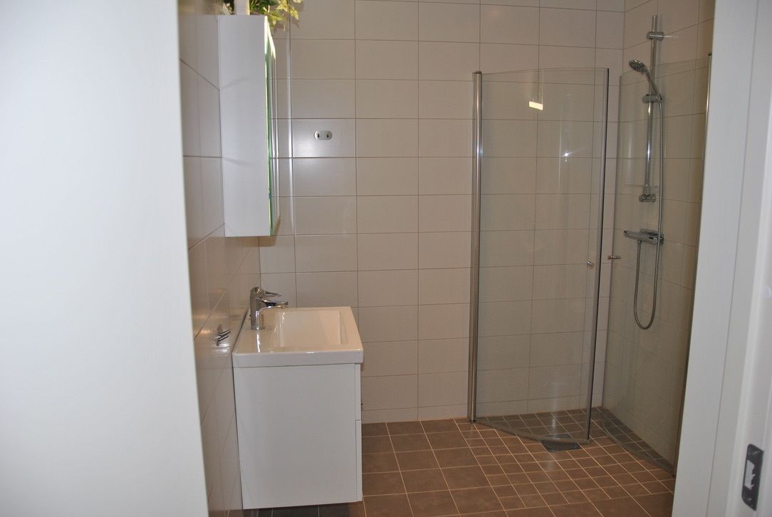 A bathroom with a white sink, a glass shower enclosure, and tiled walls.