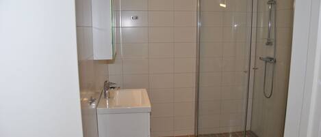A bathroom with a white sink, a glass shower enclosure, and tiled walls.
