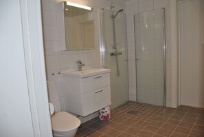 A bathroom with a toilet, sink, mirror, and shower. - Sjöhuset (Ellos)