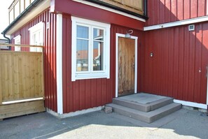 A red building with a white-framed window and a wooden door. - Sjöhuset (Ellos)
