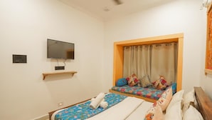 Habitación de hotel con dos camas, un televisor y una ventana con cortinas.