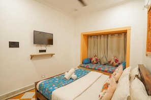Une chambre d’hôtel avec deux lits, une télévision et une fenêtre avec des rideaux.