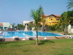 Relax by the pool surrounded by lush greenery and comfortable lounge chairs.
