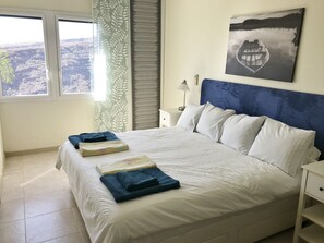 Relax in a spacious room with a large bed, nightstand, and window offering a mountain view.