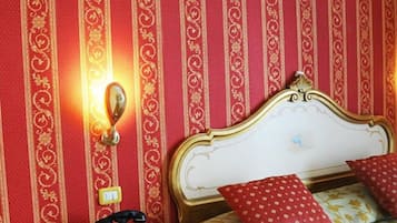 A room with a bed, a nightstand, and a wall with vertical stripes.